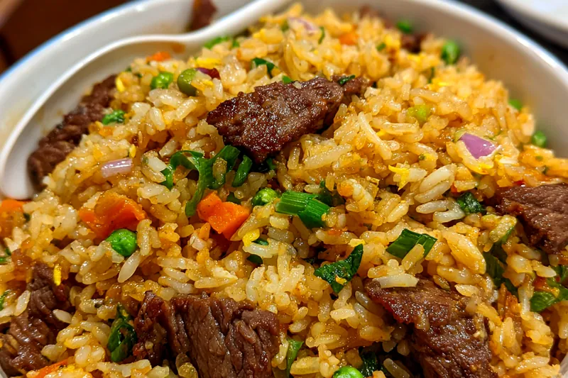 A dynamic shot of Chef Mitchell skillfully stir-frying beef and vegetables in a sizzling hot wok.
