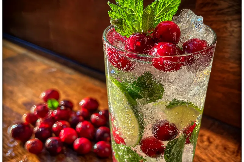 A bartender skillfully mixing ingredients to create the perfect Festive White Christmas Mojitos.