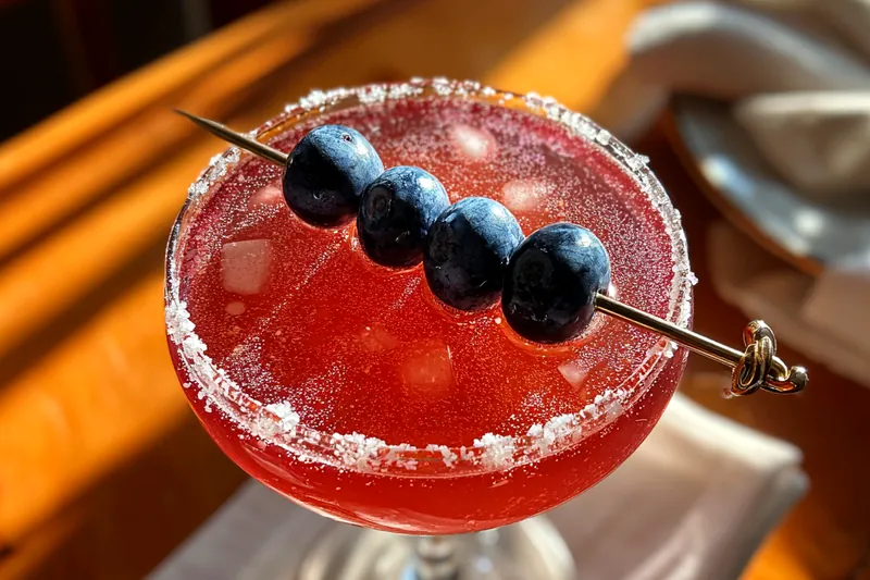 A close-up of the cocktail shaker filled with blueberries, vodka, and lemon juice being shaken for the Refreshing Blueberry Lemon Martini.